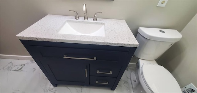 bathroom with toilet, marble finish floor, and vanity