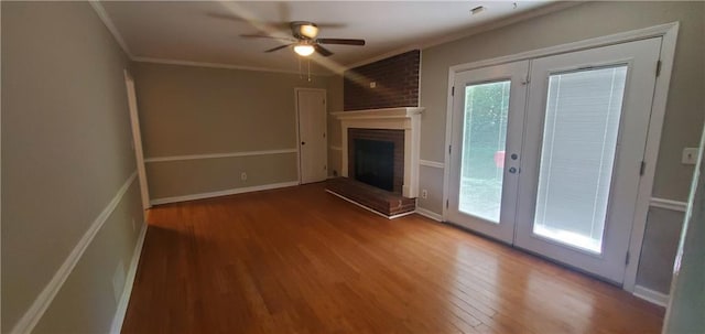 unfurnished living room featuring wood finished floors, french doors, crown molding, a brick fireplace, and ceiling fan