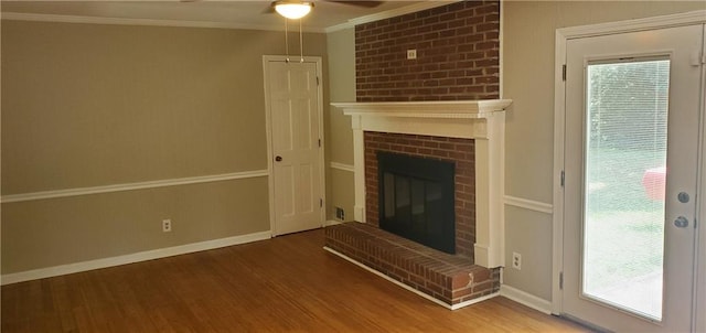 unfurnished living room with crown molding, ceiling fan, baseboards, a fireplace, and wood finished floors