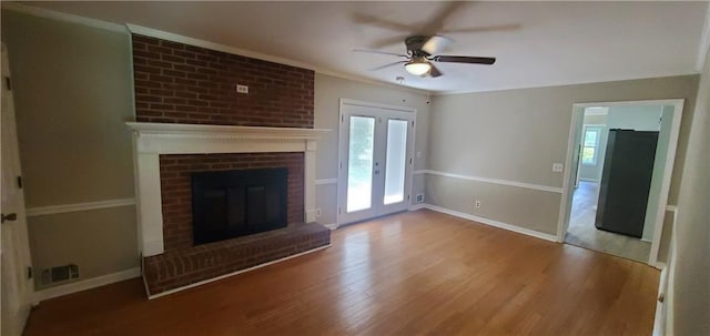 unfurnished living room featuring a fireplace, crown molding, wood finished floors, and baseboards