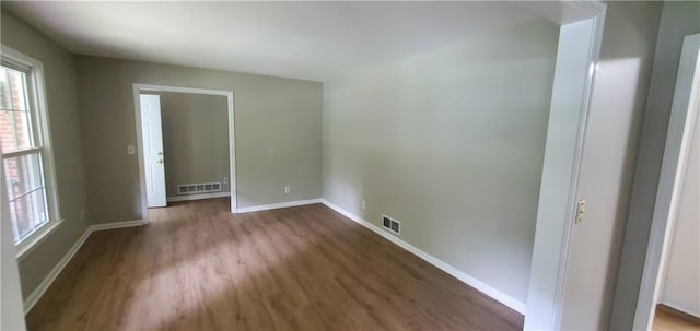 spare room featuring visible vents, baseboards, and wood finished floors