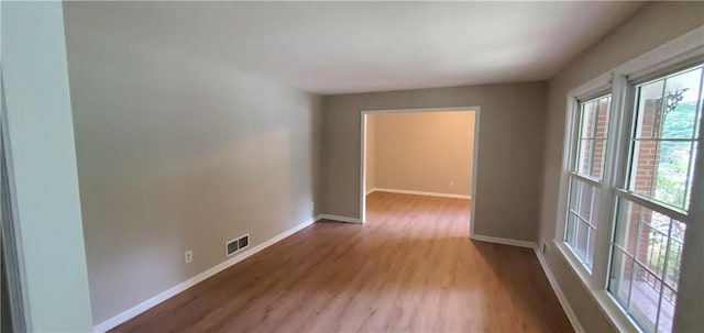 unfurnished room featuring wood finished floors, baseboards, and visible vents