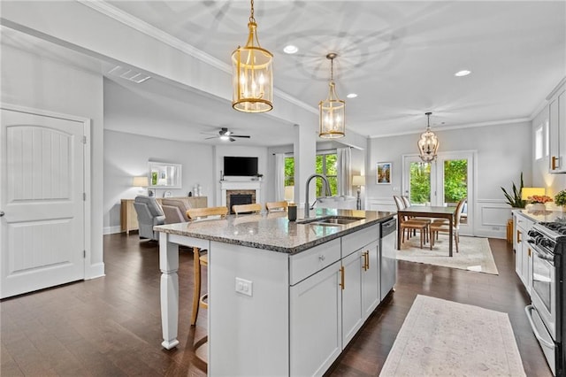 kitchen featuring a sink, appliances with stainless steel finishes, stone countertops, a fireplace, and ornamental molding