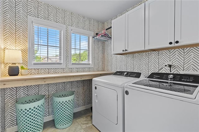 laundry area with wallpapered walls, separate washer and dryer, and cabinet space