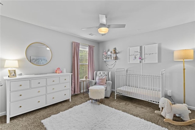 bedroom with a nursery area, carpet, a ceiling fan, and baseboards