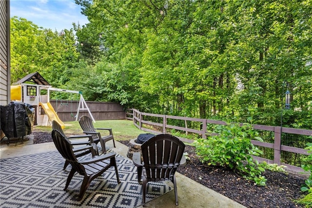 view of patio / terrace with a playground, an outdoor fire pit, and fence