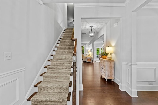 staircase with wood finished floors and a chandelier