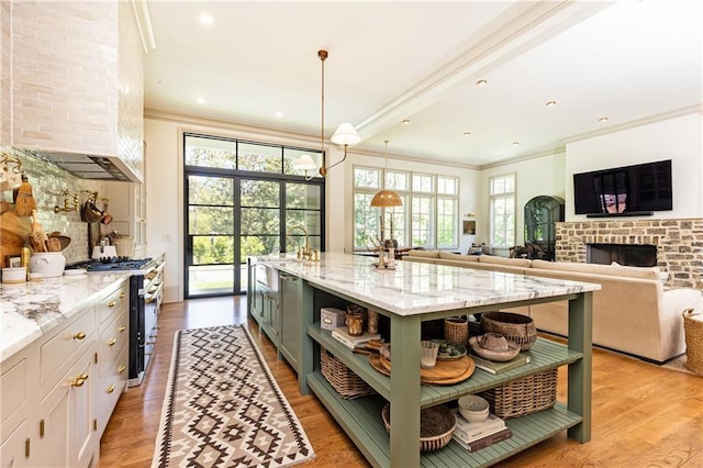 kitchen with open shelves, light stone countertops, high end stainless steel range, ornamental molding, and light wood-style flooring