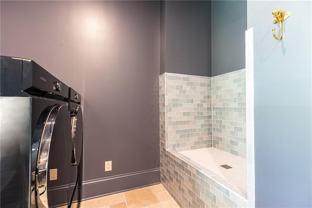 clothes washing area with light tile patterned floors and washer and dryer