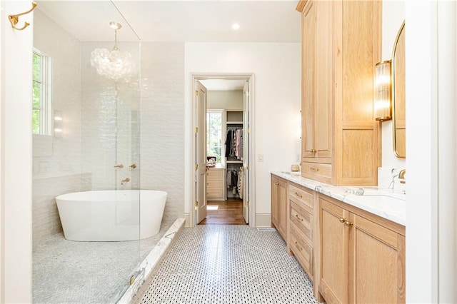 full bath featuring a freestanding bath, vanity, a spacious closet, and a notable chandelier