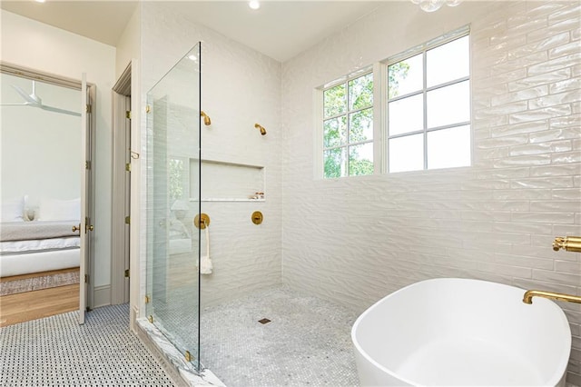ensuite bathroom with tile walls, recessed lighting, connected bathroom, a freestanding bath, and a stall shower
