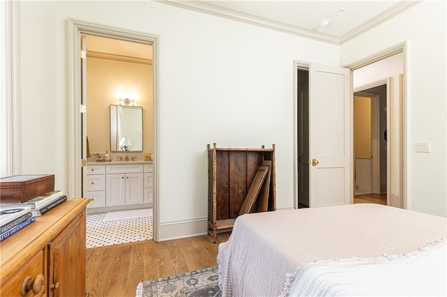 bedroom featuring baseboards, ornamental molding, light wood-style flooring, and ensuite bath