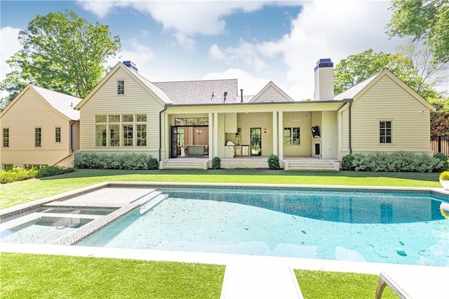 rear view of property with a hot tub, an outdoor pool, a yard, and a chimney