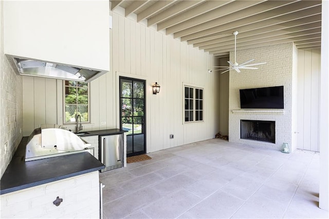 view of patio / terrace with a ceiling fan, exterior kitchen, a fireplace, a sink, and a grill