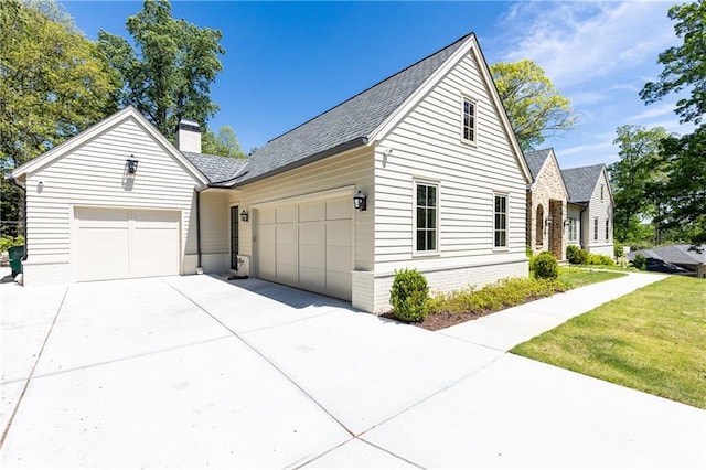 view of property exterior with roof with shingles, an attached garage, a chimney, a yard, and driveway