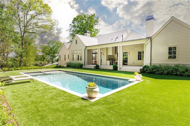 rear view of property featuring ceiling fan, a patio, an outdoor pool, a chimney, and a lawn