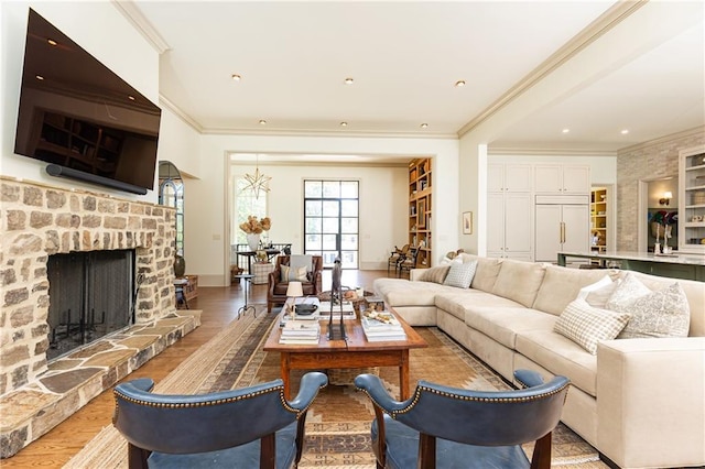 living room with crown molding, baseboards, a fireplace with raised hearth, and light wood-style flooring