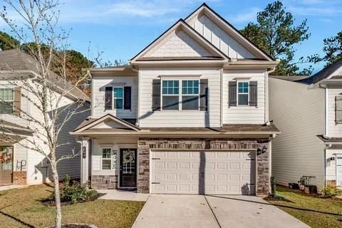 craftsman house with a garage, stone siding, driveway, and a front lawn