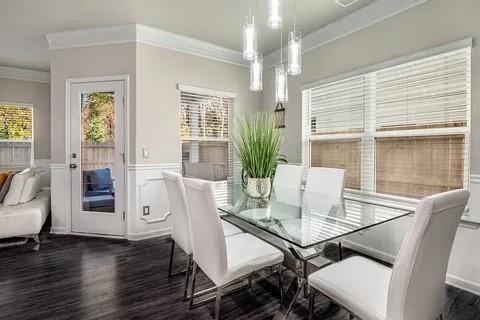 dining room featuring a wainscoted wall, dark wood-type flooring, a decorative wall, and crown molding