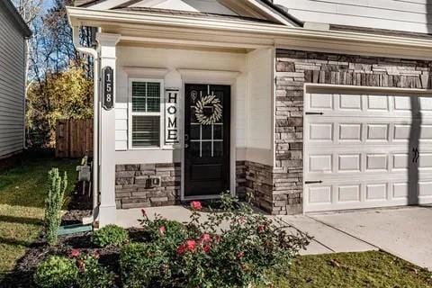 property entrance featuring a garage, stone siding, and concrete driveway