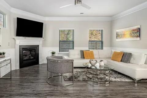 living room with a wainscoted wall, dark wood-style flooring, a glass covered fireplace, and crown molding