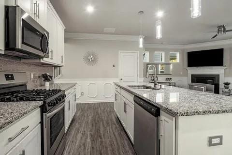 kitchen with stainless steel appliances, white cabinets, a kitchen island with sink, and hanging light fixtures