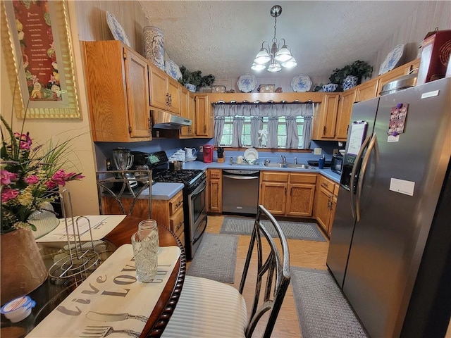 3723 Raiders Ridge Dr, Lithonia, GA 30038 - kitchen with appliances with stainless steel finishes, under cabinet range hood, a chandelier, a sink, and brown cabinetry