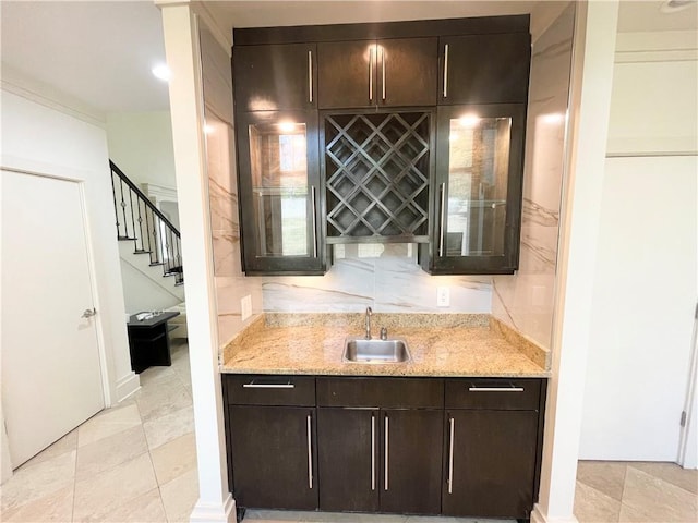 bar with light stone countertops, sink, and dark brown cabinets