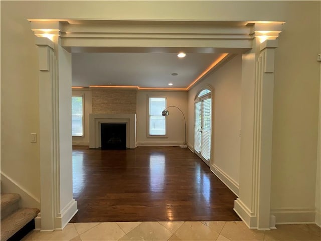 unfurnished living room featuring hardwood / wood-style floors, a large fireplace, and ornamental molding