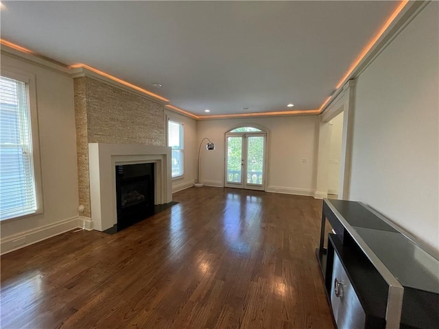 unfurnished living room featuring dark hardwood / wood-style flooring, a fireplace, a healthy amount of sunlight, and ornamental molding