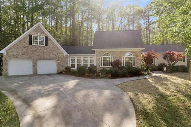 cape cod home featuring brick siding, roof with shingles, driveway, and an attached garage