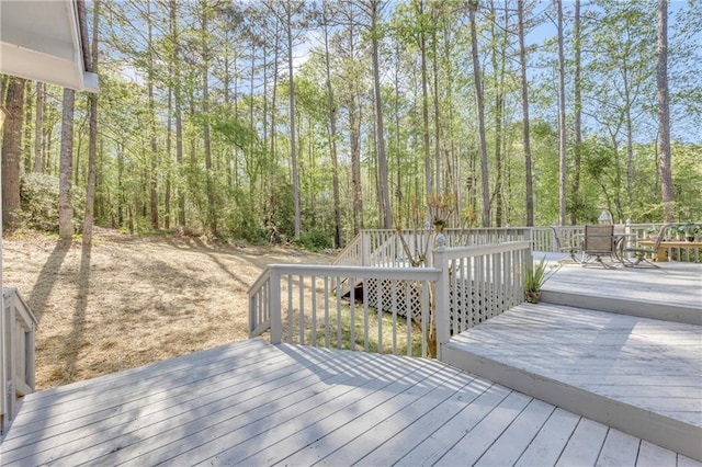 wooden deck featuring outdoor dining space and a wooded view