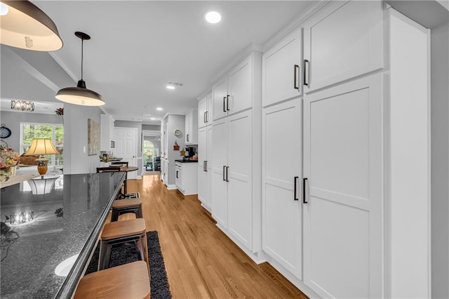 kitchen featuring white cabinets, plenty of natural light, light wood-type flooring, recessed lighting, and dark stone counters