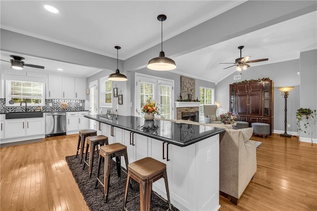 kitchen featuring ceiling fan, dark countertops, dishwasher, and a fireplace