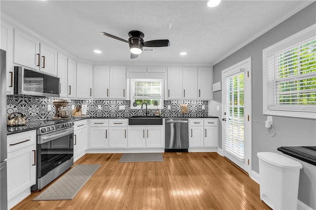kitchen with appliances with stainless steel finishes, a sink, white cabinetry, and dark countertops