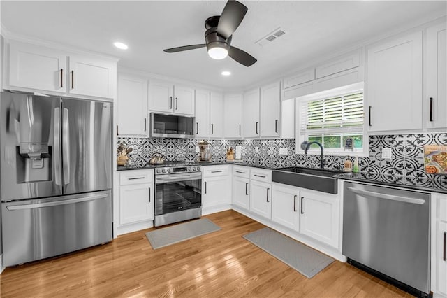 kitchen featuring white cabinetry, visible vents, appliances with stainless steel finishes, a sink, and dark countertops