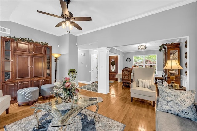 living area with visible vents, ornamental molding, a ceiling fan, light wood-style floors, and lofted ceiling