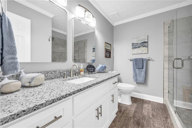 bathroom with baseboards, ornamental molding, toilet, a shower stall, and vanity