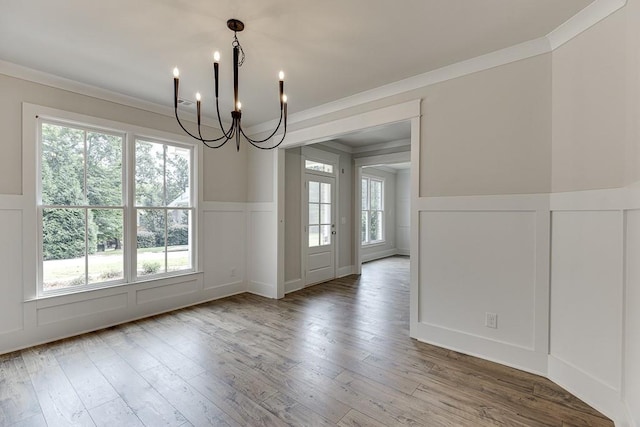 unfurnished dining area featuring a chandelier, hardwood / wood-style flooring, and crown molding