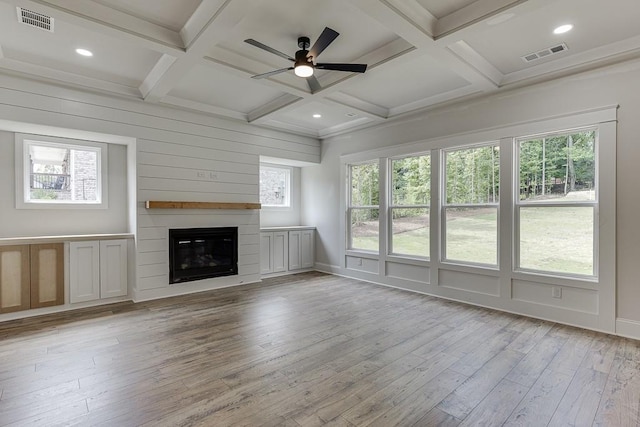 unfurnished living room featuring beamed ceiling, a large fireplace, light hardwood / wood-style flooring, and coffered ceiling