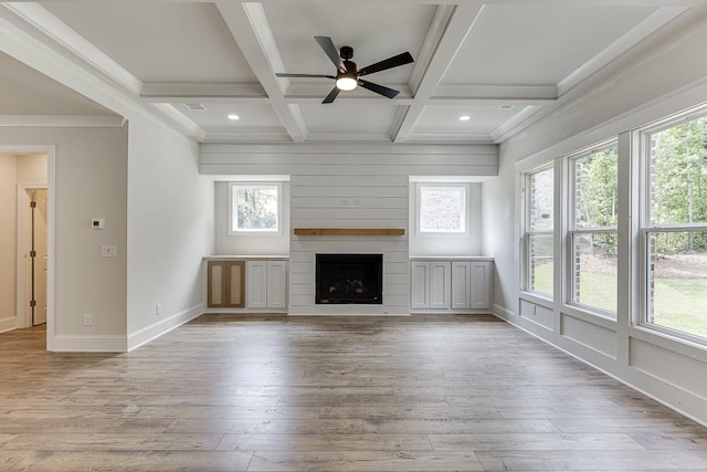 unfurnished living room with coffered ceiling, a large fireplace, crown molding, light hardwood / wood-style flooring, and beamed ceiling