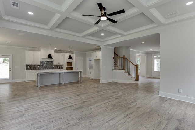 unfurnished living room with ceiling fan, light wood-type flooring, ornamental molding, and coffered ceiling