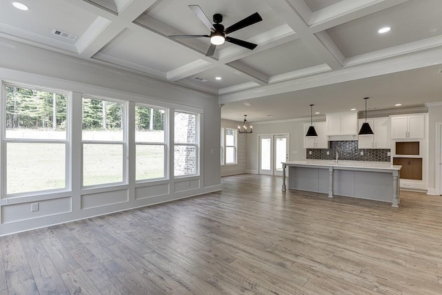 unfurnished living room featuring light wood-type flooring, coffered ceiling, ceiling fan with notable chandelier, crown molding, and beamed ceiling