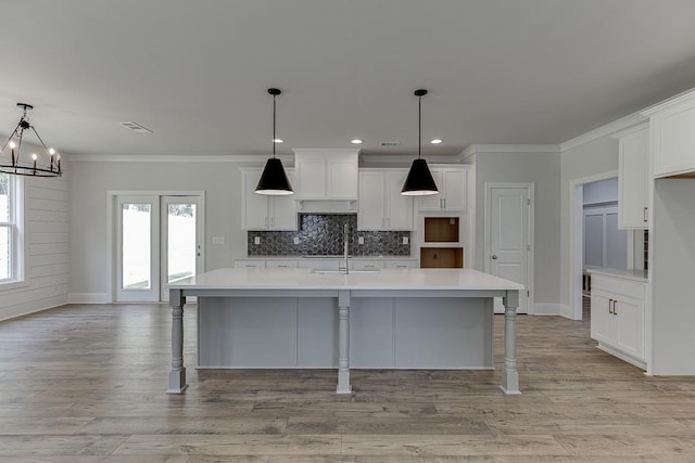 kitchen with a center island with sink, a kitchen breakfast bar, pendant lighting, and white cabinets