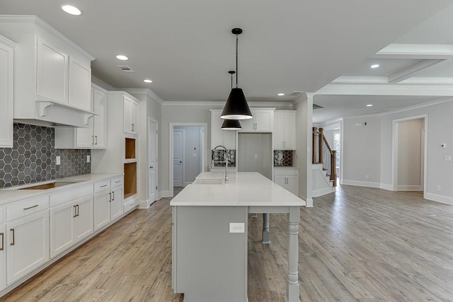 kitchen with white cabinetry, crown molding, and an island with sink