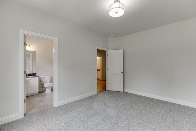 unfurnished bedroom featuring connected bathroom and light colored carpet