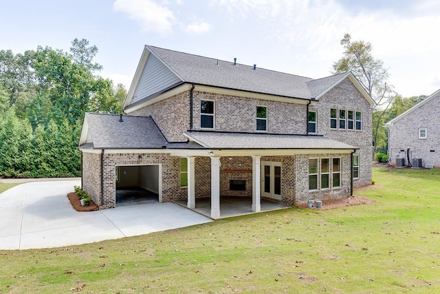 back of property with a lawn, central air condition unit, a patio, and a garage