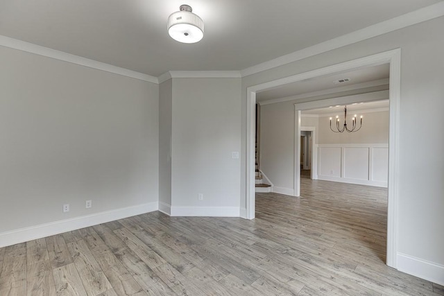 spare room featuring a chandelier, light hardwood / wood-style flooring, and crown molding