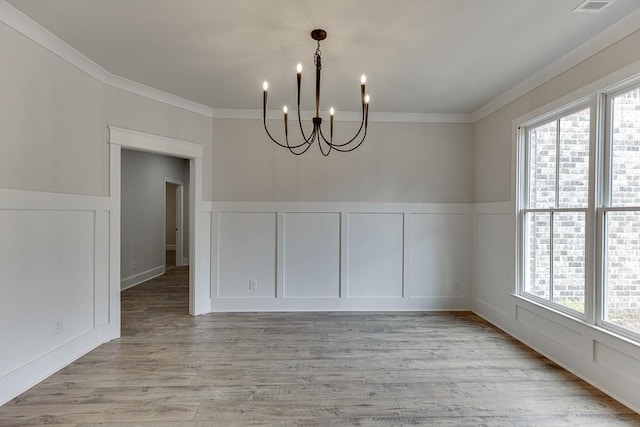 unfurnished dining area featuring crown molding, a healthy amount of sunlight, and an inviting chandelier