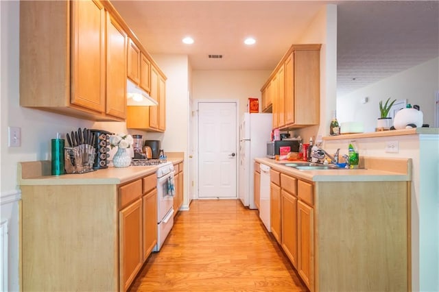 kitchen featuring white appliances, light brown cabinetry, sink, and light wood-type flooring